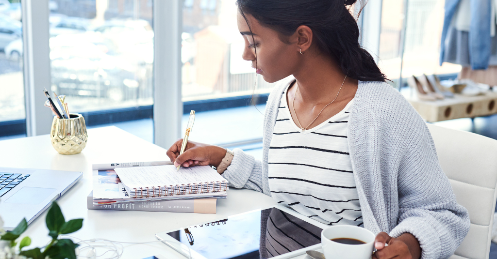 lady writing notes with laptop and notepad